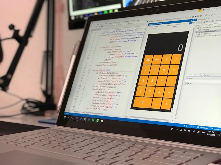 A person working on a laptop with a dark-themed coding interface displayed on the screen, featuring lines of colorful code and text. The individual’s hands are visible, with one hand positioned over